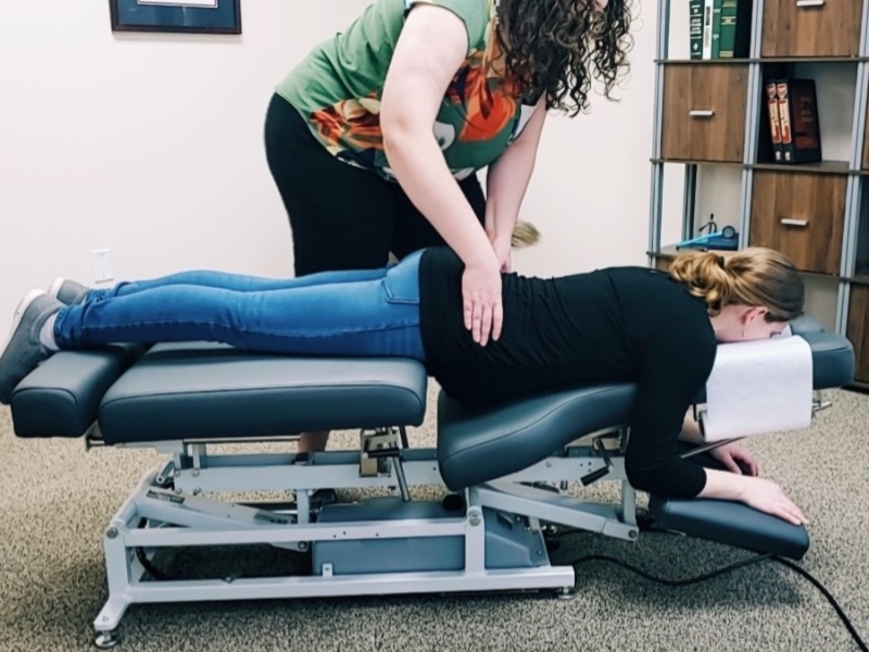 Female chiropractor adjusting female patient, who is laying face-down on a chiropractic table