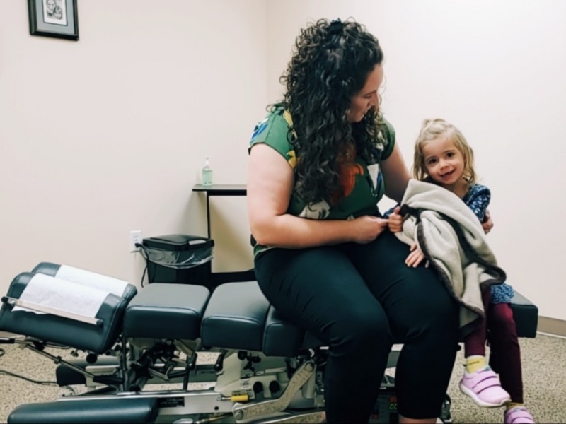Family Chiropractic doctor sitting with little girl